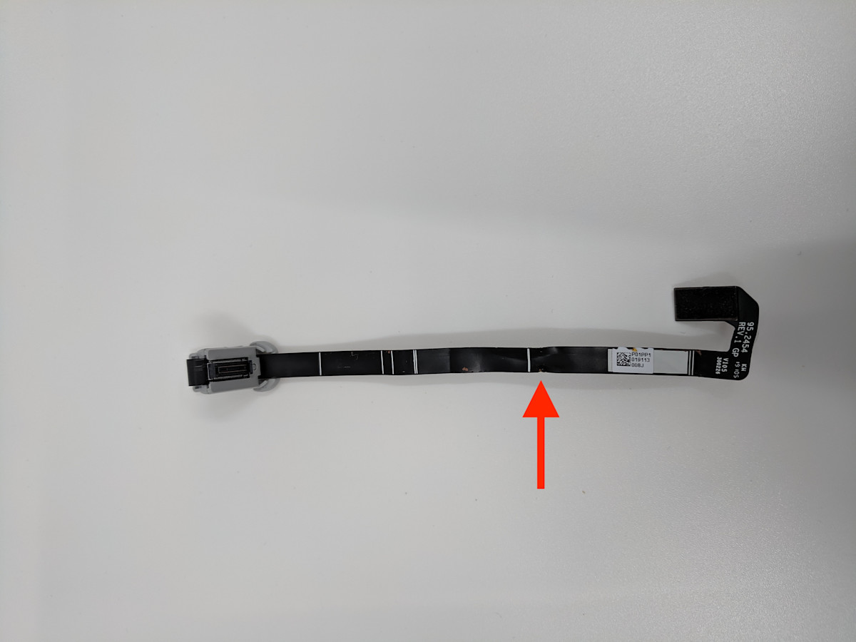 Peephole cam flex cable with a black arrow that points to a dent in the flex cable. 