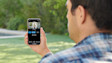 Person viewing security camera feed on smartphone outdoors