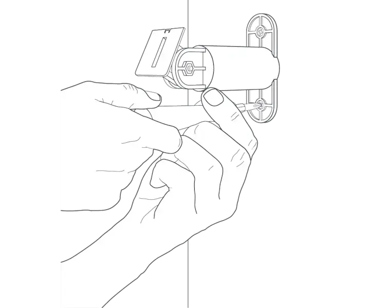 A hand holding a screwdriver and tightening the screw on the base of the mounting arm to secure it to the wall.