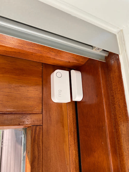 Contact Sensor (2nd Gen) mounted on wooden door frame with metal track above