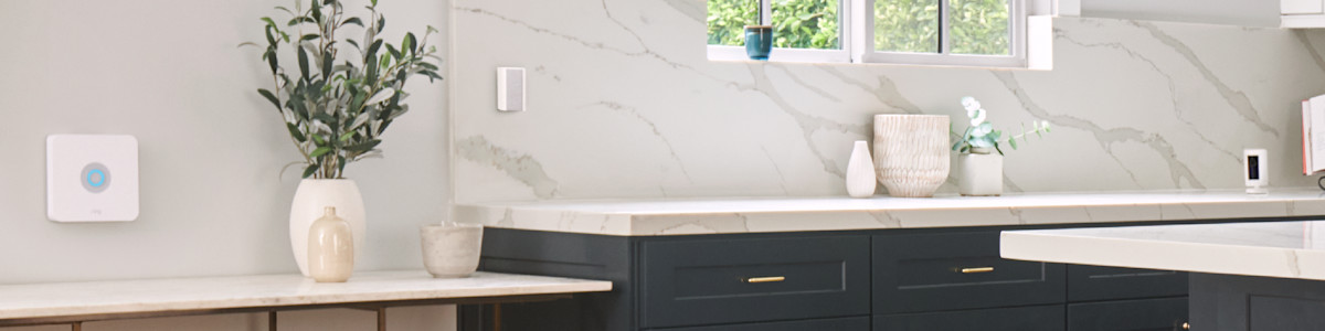 Modern kitchen with navy cabinets and marble worktops displaying a Ring security camera