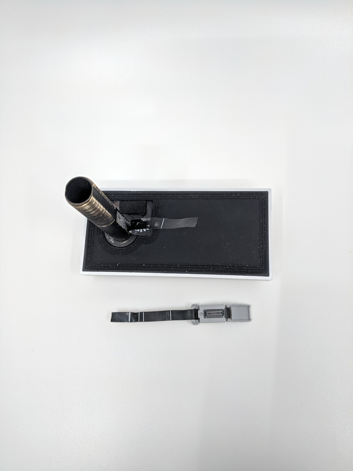 Peephole components on white surface to display a torn flex cable