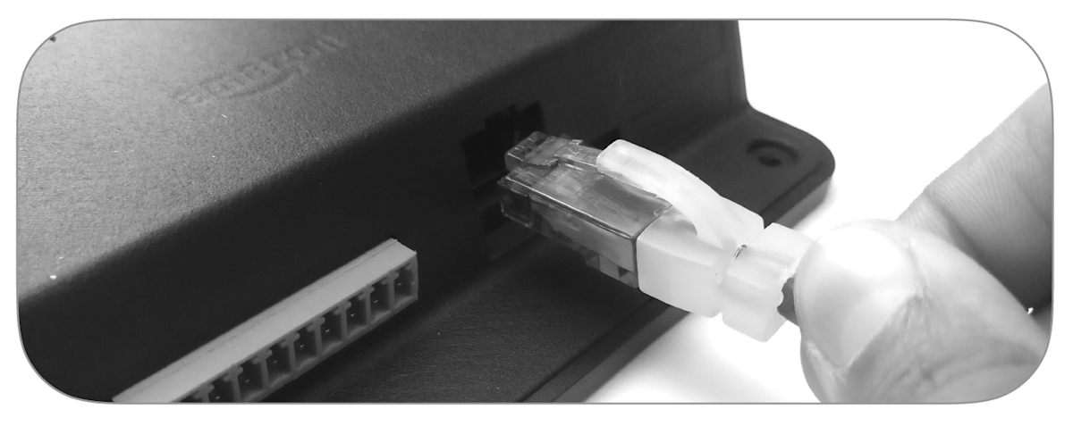 Hand holding an Ethernet cable to plug into a black electronic device. 