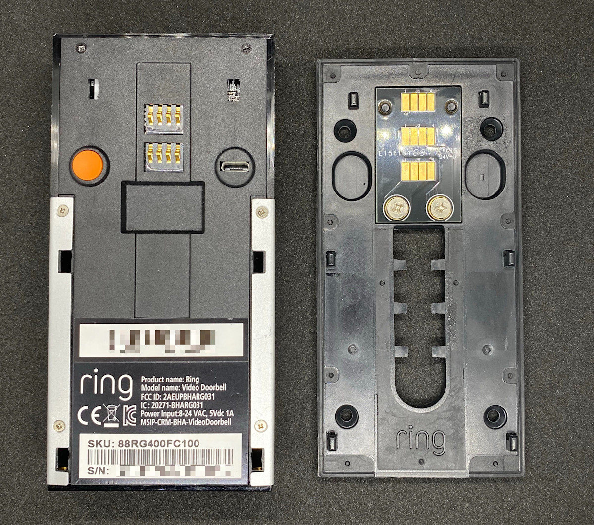 The back of the Ring Video Doorbell (1st Generation) showing the orange button. The mounting plate with 3 gold colored sensors at the top.
