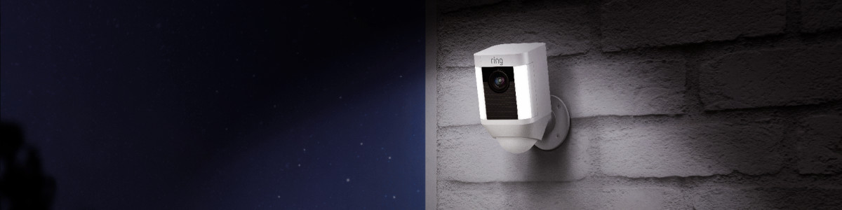 Ring Spotlight Cam (1st Generation) mounted on a wall outside lighting up a dark night.