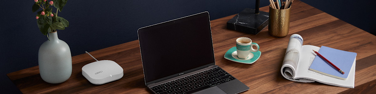 A home office desk with an eero router and laptop.