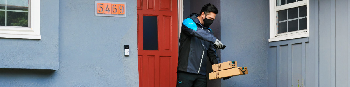 An Amazon delivery person scanning boxes on a homeowner's doorstep.