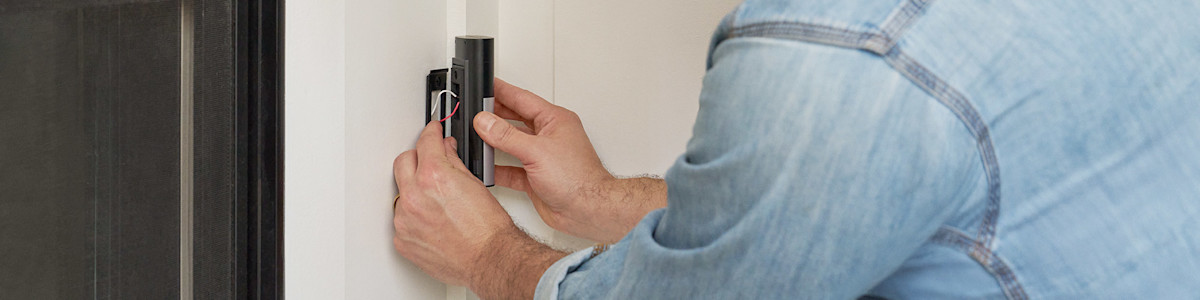 Hands installing a Wired Video Doorbell Plus (2nd Gen) on white wall
