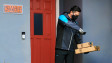 An Amazon delivery person scanning boxes on a homeowner's doorstep