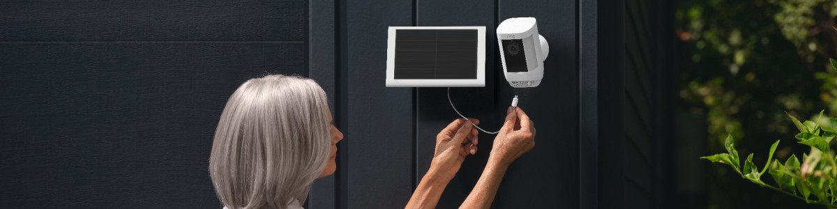 A homeowner plugging Ring Solar Panel into Spotlight Cam Pro Solar