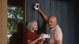 A couple installing their Spotlight Cam Pro Plug-In on their front porch wall