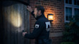 A security guard is shining a torch and checking a gate.