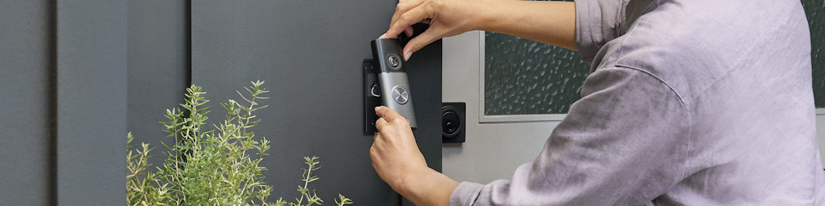 Hands installing a Wired Video Doorbell Pro (3rd Gen) on modern gray door