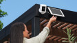 A homeowner making final installation adjustments their new Ring Spotlight Cam Plus Solar.